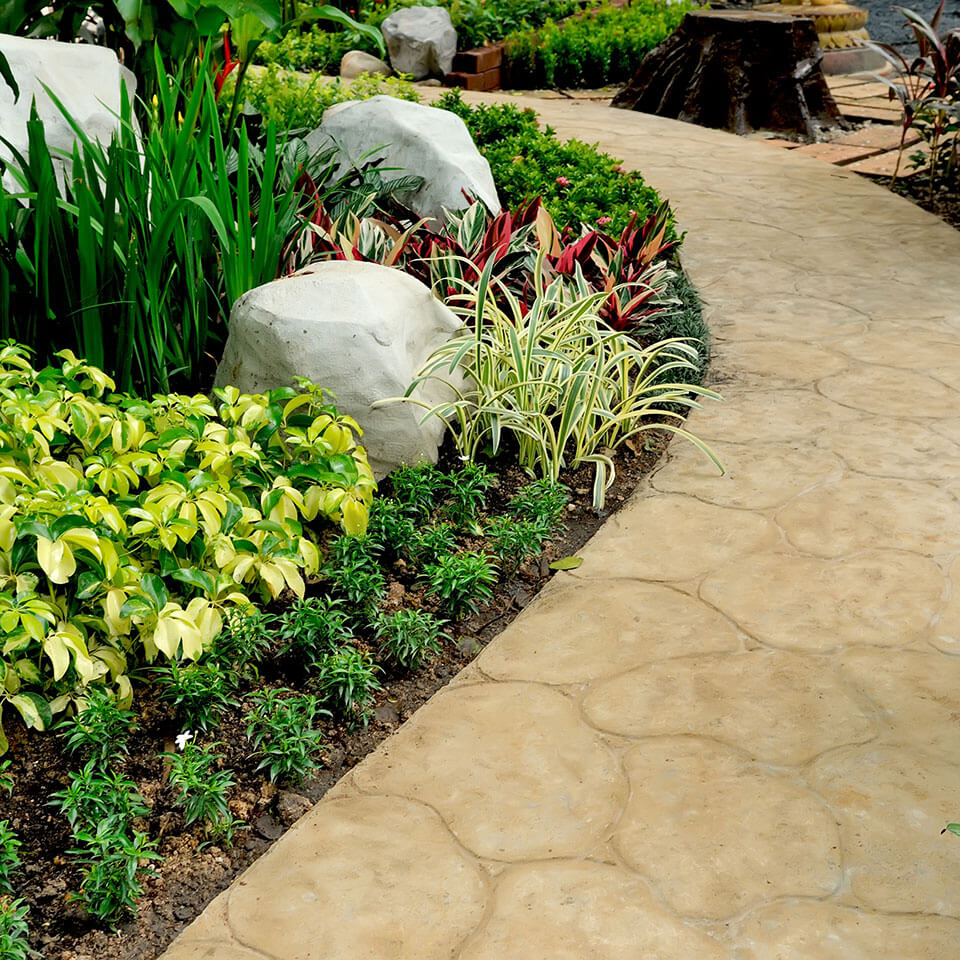 Hardscape and landscape design with textured stone walkway, decorative rocks, and garden